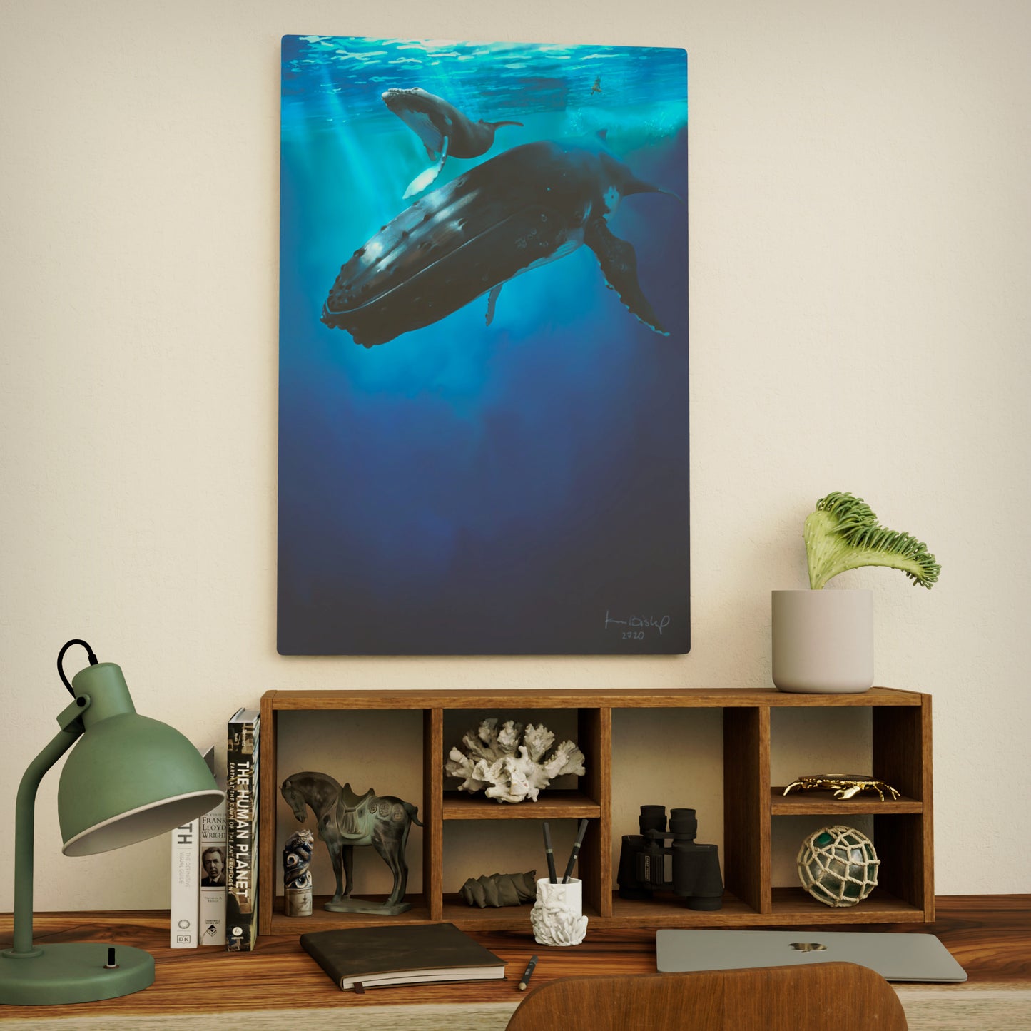 metal print of a whale and calf underwater hanging on a wall above a wooden shelf.