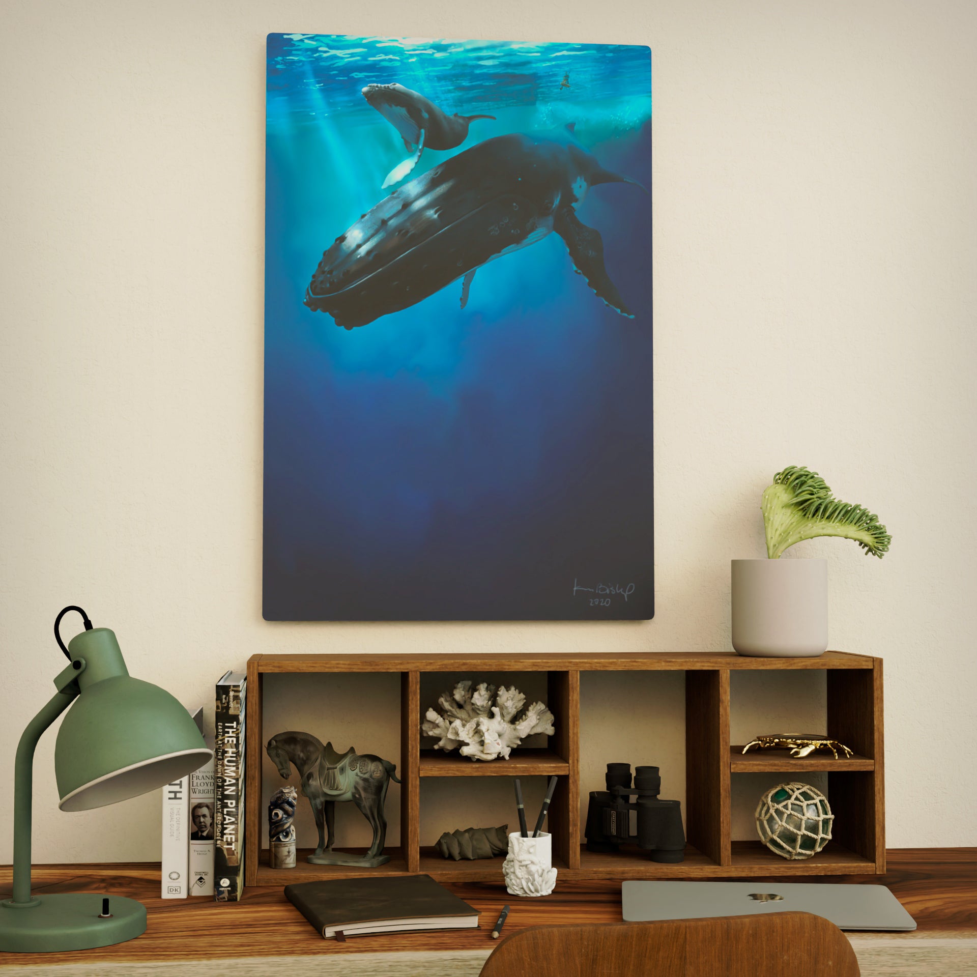 metal print of a whale and calf underwater hanging on a wall above a wooden shelf.